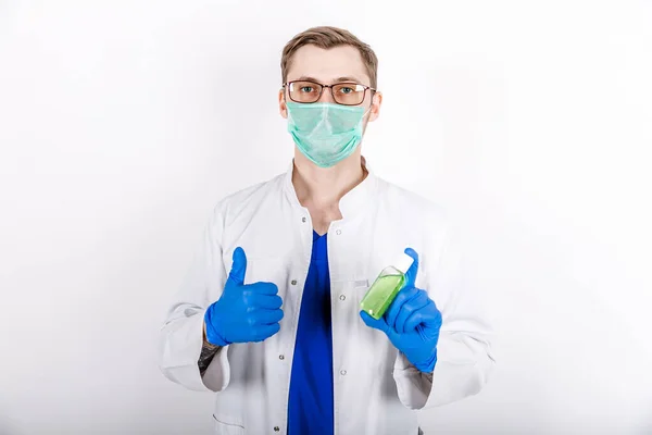 Doktor antiseptik kullanmamızı öneriyor. Beyaz önlüklü, eldivenli ve koruyucu maskeli bir doktor. Dezenfektan kullanımı. Beyaz arka plan. Hijyen ürünleri. COVID-19 Dezenfeksiyonuna karşı koruma