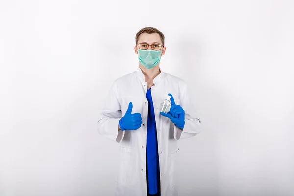 Doktor antiseptik kullanmamızı öneriyor. Beyaz önlüklü, eldivenli ve koruyucu maskeli bir doktor. Dezenfektan kullanımı. Beyaz arka plan. Hijyen ürünleri. COVID-19 Dezenfeksiyonuna karşı koruma