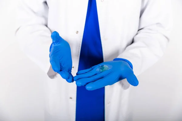 Treatment of blue rubber gloves with an antiseptic against bacteria. The doctor uses an antiseptic with blue gloves. Doctor in a white coat and protective gloves. The use of a disinfectant with gloves