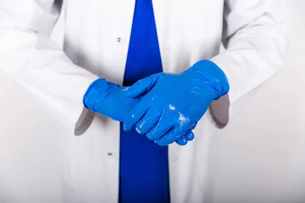 Bakterilere karşı antiseptik içeren mavi lastik eldiven tedavisi. Doktor mavi eldivenli bir antiseptik kullanır. Beyaz önlüklü ve koruyucu eldivenli bir doktor. Eldivenli dezenfektan kullanımı.