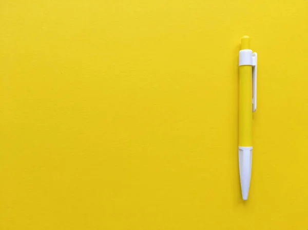 Yellow and white pen on yellow background. Minimalistic flat lay with copy space. Stock photo.