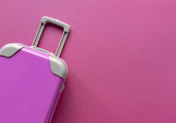 Plastik merah muda koper pada pastel kertas background.Travel konsep liburan petualangan musim panas. Datar berbaring dengan satu hal sederhana. Foto cerah stok. — Stok Foto