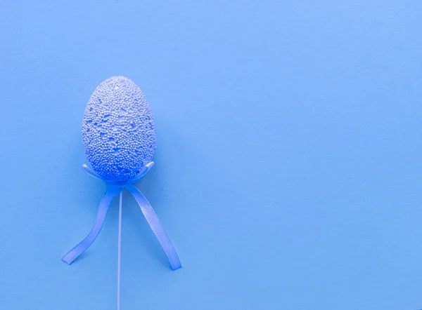 Easter minimalistic banner in blue color. Flat lay with copy space. Single egg at the left. Stock photo.