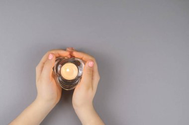 Manikür üst görüşlü bir kızın elleri. Kristal bir şamdanın içindeki bir mumun ellerinde