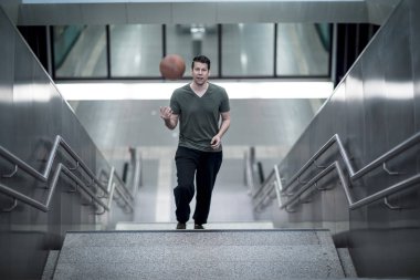 Merdivenlerden yukarı bir basketbol ile yürüyen adam