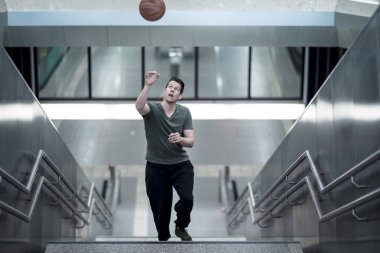 Merdivenlerden yukarı bir basketbol ile yürüyen adam