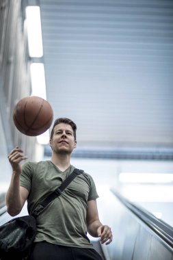 Bir basketbol ile merdivenden aşağı yürüyen adam