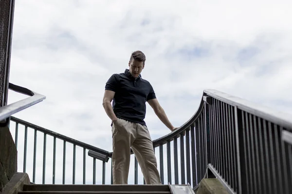 Homem em pé em uma escada ao ar livre — Fotografia de Stock