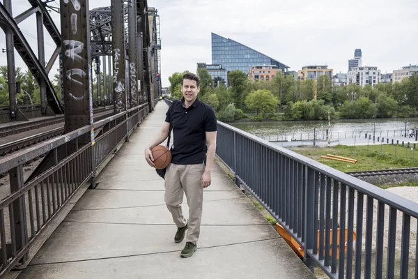 Homme avec un ballon de basket posant près des voies ferrées — Photo