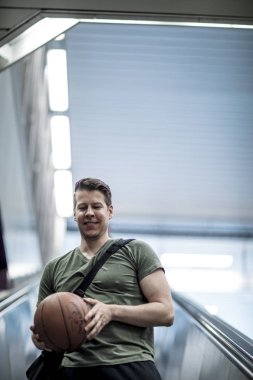 Bir basketbol ile merdivenden aşağı yürüyen adam