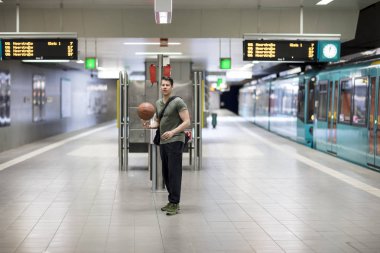 Bir metro istasyonu platformu ayakta bir basketbol adamla