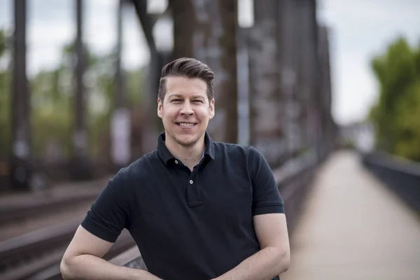 Portret van een knappe Man die zich voordeed op de brug van een stad — Stockfoto