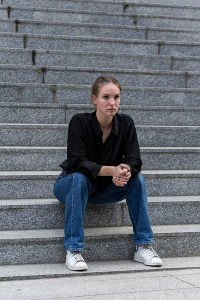 坐在户外大理石台阶上的年轻女子 — 图库照片