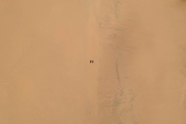 Çölde tek başına yürüyen iki kişi.