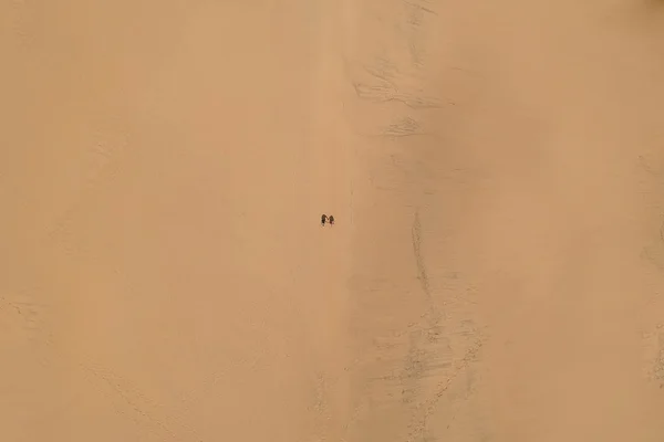 two people walking alone in desert, top view drone shot
