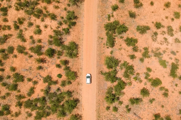 top view shot of a white car driving a long road in the desert