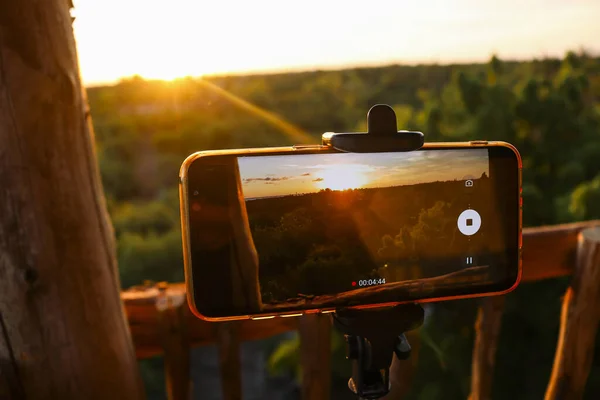 Smartphone opnemen van een zonsondergang van boomhut — Stockfoto