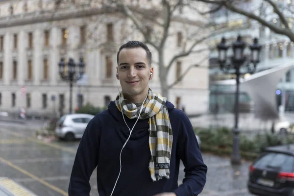 Νεαρός Καυκάσιος Άνδρας Χαμογελά Ακούγοντας Ακουστικά Στο Σκηνικό Της Πόλης — Φωτογραφία Αρχείου