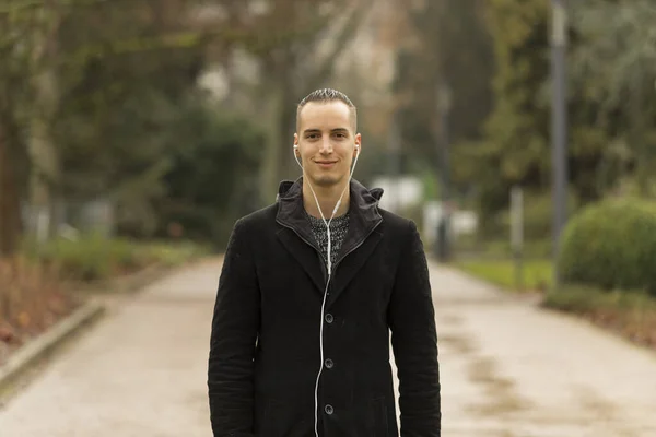 Fiatal Kaukázusi Férfi Fülhallgatót Hallgat Amint Ősszel Pózol Parkban Közepes — Stock Fotó