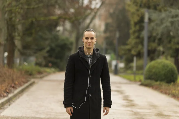 Pria Muda Kaukasia Tersenyum Dan Mendengarkan Earphone Berjalan Jalan Taman — Stok Foto