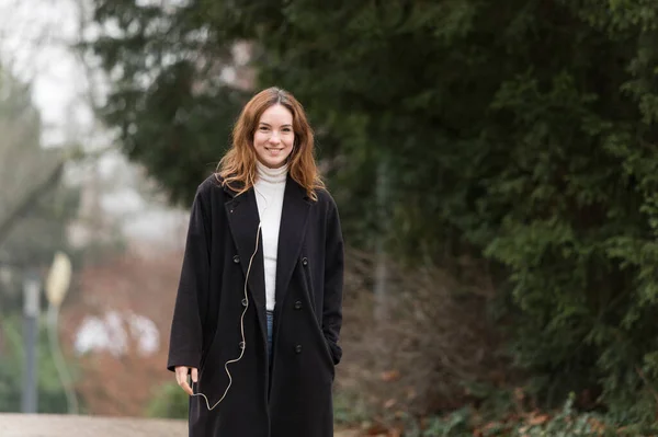 Young Woman Wearing Long Black Coat Smiling Camera Public Park — Stock Photo, Image