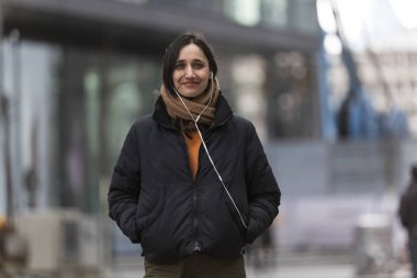 Zeytin tenli genç bir kadın şehrin dışında kameraya gülümsüyor.. 