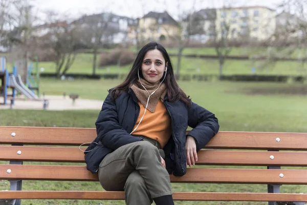 Young Urbanite Indian Woman Sitting Park Bench Listening Earphones Smiling — Stock Photo, Image