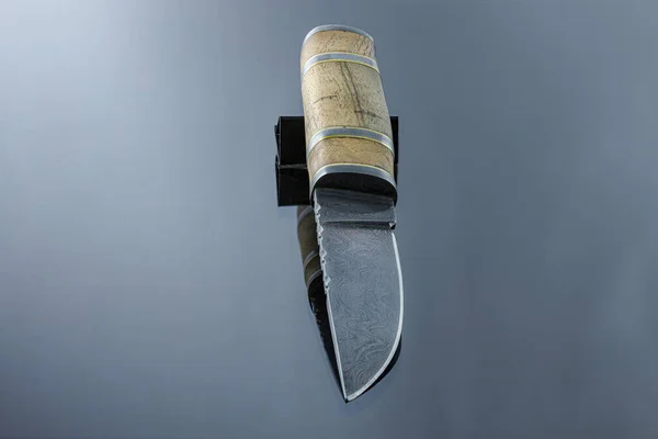 handmade carving knife on a mirrored surface, damascus blade, wood handle and damask steel spacers