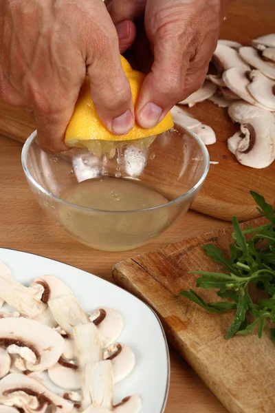 Making sauce for carpaccio. Squeezing juice of lemon pulp into small mixing bowl.