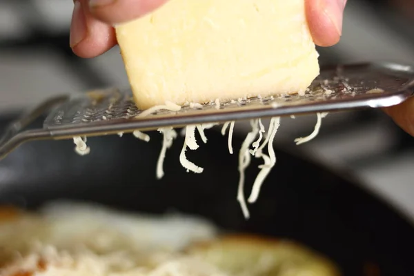 Making sunny side up eggs with fried potato and grated cheese