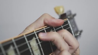 Eller gitar fretboardunda ve yatak başlığında akorlar çalıyor. Gitarist gitarda şarkı söylüyor..
