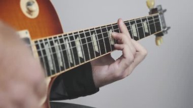 Erkek eli elektro ya da akustik gitar çalıyor. Gitarda rock ve blues akorları çalıyorum. Eller, parmaklar gitar panosunda.