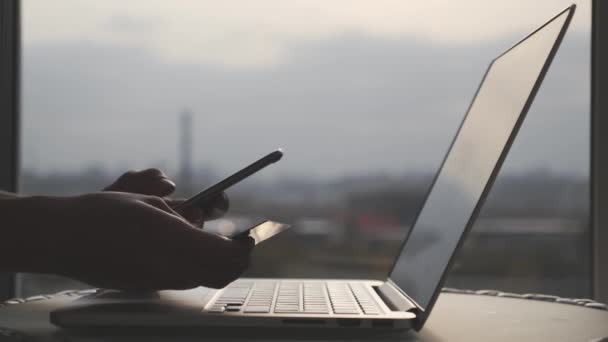 Las manos femeninas con tarjeta de débito de crédito y las compras de teléfonos celulares en línea introduciendo dígitos y código cvv con computadora portátil. Concepto de compras online . — Vídeos de Stock