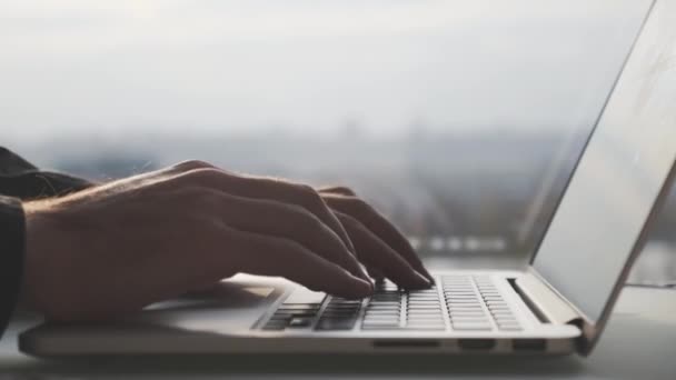 Manos masculinas escribiendo y utilizando el panel táctil en el teclado del ordenador portátil contra la ventana en la oficina. Concepto empresarial — Vídeos de Stock