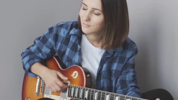 Aantrekkelijke mooie vrouw met elektrische gitaar in handen die rock- en jazzballads speelt en zich vermaakt. Muziekconcept — Stockvideo