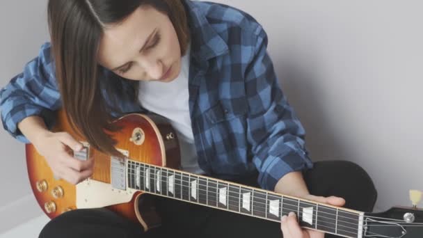 Young attractive female with electric guitar practicing songs before concept. Hands playing on guitar fretboard pulling strings and chords. Music concept — Stock Video