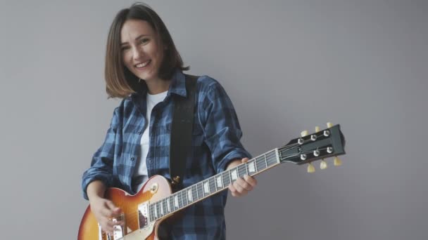 Feliz hermosa mujer con guitarra eléctrica toca rock y blues canción vistiendo camisa casual azul sonriendo y riendo. Guitarrista de rock practicando música — Vídeos de Stock