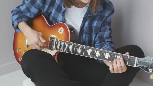 Mani femminili che suonano la chitarra elettrica mentre sono sedute. Donna pratica il suo gioco sulla chitarra elettrica indossando abiti casual. Concetto industria musicale — Video Stock