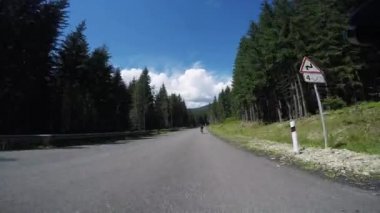 Bisikletçi. Pov, orijinal bakış açısı. Profesyonel erkek bisikletçiler dağlarda yol bisikleti sürerler. Genç triatlon sporcuları için sıkı bir eğitim. Bisiklet konsepti. Bisiklet üzerinde çalışma