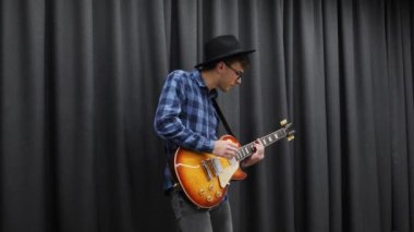Rock N Roll gitaristi elektro gitarda çalıyor. Genç bir müzisyen evde şarkı söylüyor. Müzik aletleri konsepti. Erkek hippi gitarda akor çalıyor.