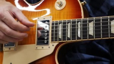 Adam gitarla yakından çalıyor. Gitarist elektro gitarda şarkı ve solo söylüyor. Profesyonel gitar çalıyor. Gitarda çalmayı öğrenen adam