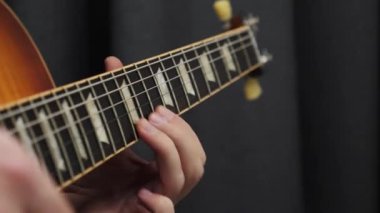 Gitarda çalan insan parmakları. Gitar panosunu kapat ve erkek eli akorları çal. Profesyonel gitar solosu. Öğretmenle müzik dersleri.