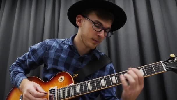 Musician playing on guitar, close up. Young cute man holding pick and performing solo on electric guitar. Music lessons. Musical instruments concept. Male enjoying playing on guitar — Stock Video