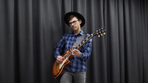 Un uomo che suona la chitarra elettrica. Giovane hippie felice millenario maschio eseguendo solo. Chitarra professionale suonare a casa. Maschio adolescente che suona la chitarra — Video Stock