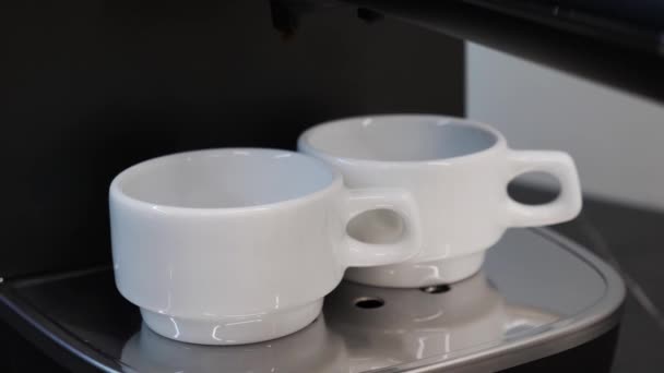 Kávéfőző gép. Közelkép a kávéfőző gép készít eszpresszót fehér poharakban. Fekete kávé eszpresszó, csészékbe öntve. Kávéáradat öntése professzionális gépből csészében — Stock videók