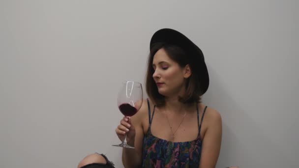 Жіночий дегустаційний келих червоного вина. Жінка п'є вино і насолоджується білим тлом. Жінка ковтає червоне вино або алкогольні напої — стокове відео