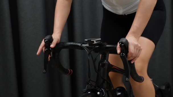 Ciclismo treino indoor no treinador inteligente. Mulher mãos segurando guidão de ciclismo pedalando fora de sela em casa fazendo exercício cardio . — Vídeo de Stock