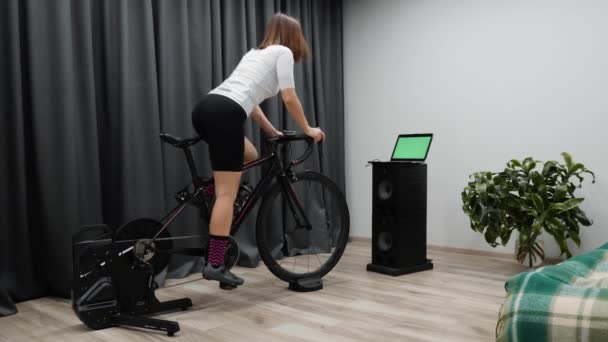 Ciclismo virtual interno. Fit mulher ciclismo passeios de bicicleta em casa em bicicleta estacionária fora de sela. Conceito de ciclismo — Vídeo de Stock