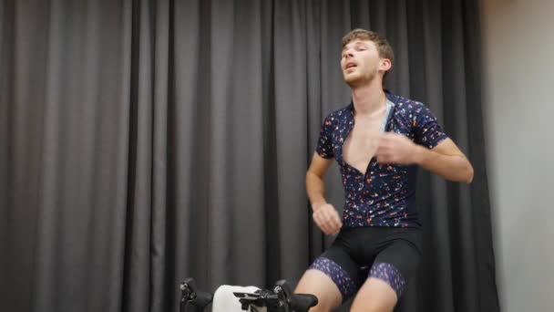 Muž trénink na kole chytrý trenér na hubnutí. Přizpůsobit mužské cyklistice na kole, pít izotonické a držet ručník uvnitř. Vnitřní virtuální cvičení koncept — Stock video