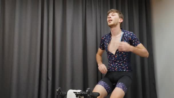 Treinamento de homem em bicicleta treinador inteligente para perder peso. Ajuste o ciclismo masculino na bicicleta, bebendo isotônico e segurando toalha dentro de casa. Conceito de exercícios virtuais internos — Vídeo de Stock